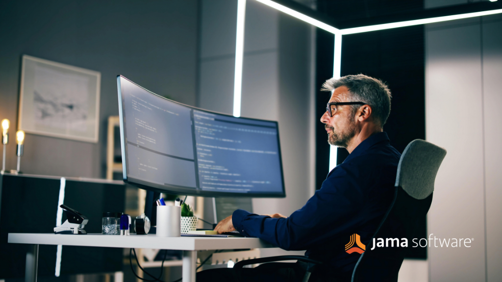 Engineer at a desk reviewing code on two monitors.